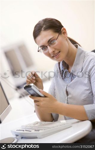 Woman in computer room using personal digital assistant and smiling