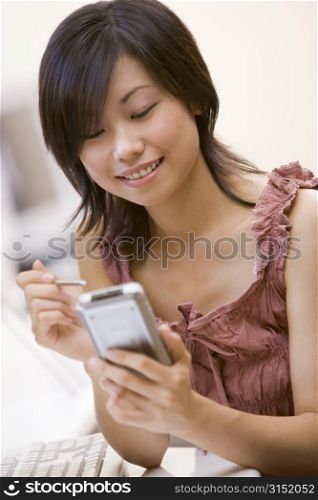 Woman in computer room using personal digital assistant smiling