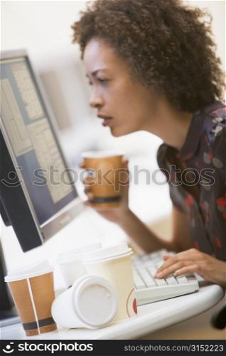 Woman in computer room with many cups of empty coffee around her