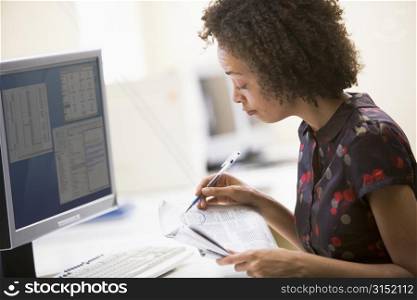 Woman in computer roon circling items in newspaper