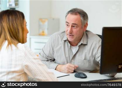 woman in consultation with mature man sat at office desk