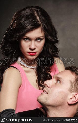 Woman in control of man, sexy female controls her guy. Studio shot on black grey background.
