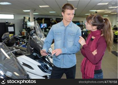 Woman in conversation with salesman in scooter showroom