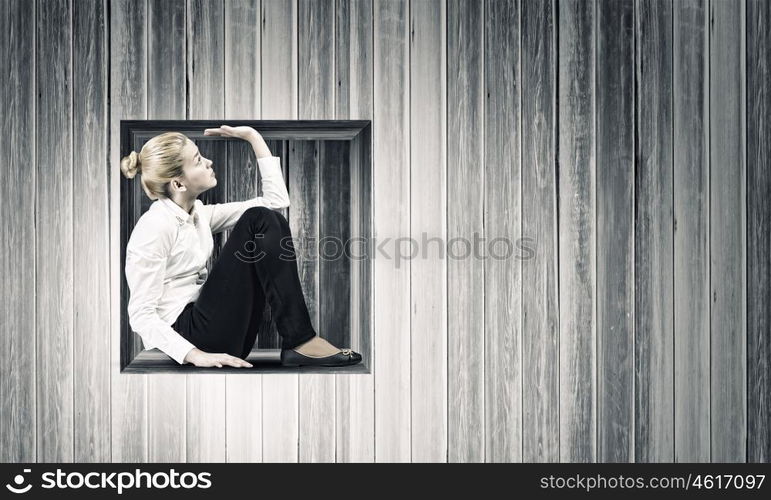 Woman in cube. Young businesswoman trapped in wooden cube in wall