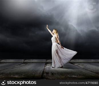 Woman in darkness. Young woman in in darkness reaching to sun light