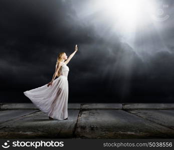 Woman in darkness. Young woman in in darkness reaching to sun light