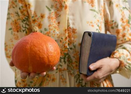 Woman In Dress Hold In Hands Little Decorative Pumpkin and Bible