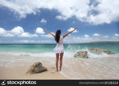 Woman in dress on beach. Beautiful young woman in dress on beach with hands raised
