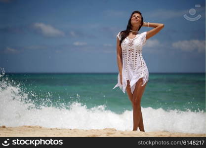 Woman in dress on beach. Beautiful young woman in dress on beach with hands raised