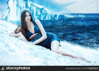 Woman in dress on the snowy beach and iceberg