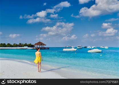 Woman in dress walking on tropical beach. Summer vacation at Maldives.