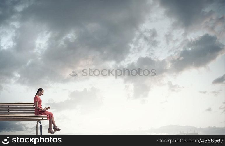 Woman in dress with book. Young woman sitting on bench and reading book