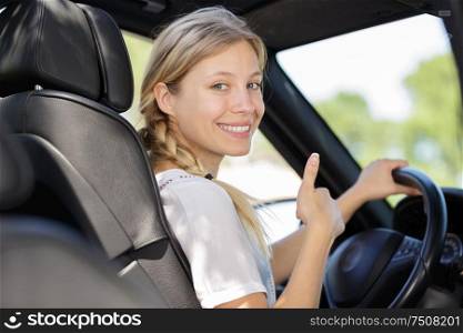 woman in drivers seat turning to make thumbs up gesture