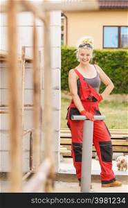 Woman in dungarees carrying and installing plastic pipes on her home construction site, building new home.. Woman installing pipes on construction site