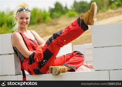 Woman in dungarees relaxing after hard work on construction site. Young female lying outdoor taking a break. Woman taking break on construction site