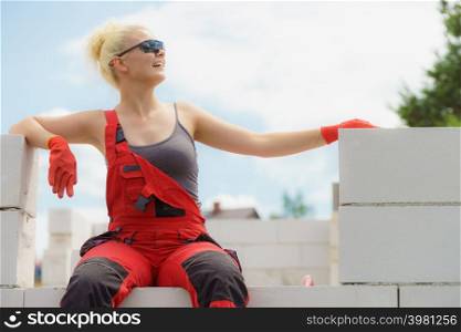 Woman in dungarees relaxing after hard work on construction site. Young female lying outdoor taking a break. Woman taking break on construction site