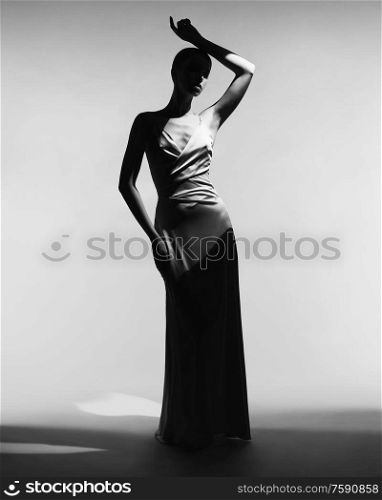Woman in elegant fashionable dress. Beautiful model pose in studio in evening clothes. Classic silk dress. Sexy lady stay on white background. Perfect young woman with classic hairstyle and makeup.