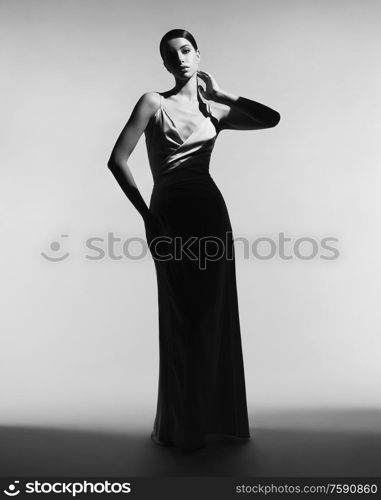 Woman in elegant fashionable dress. Beautiful model pose in studio in evening clothes. Classic silk dress. Sexy lady stay on white background. Perfect young woman with classic hairstyle and makeup.