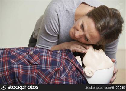 Woman In First Aid Class Checking Airway On CPR Dummy