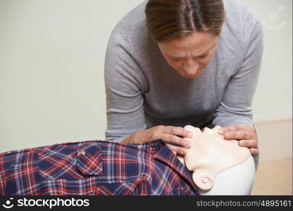 Woman In First Aid Class Performing Mouth To Mouth Resuscitation On Dummy