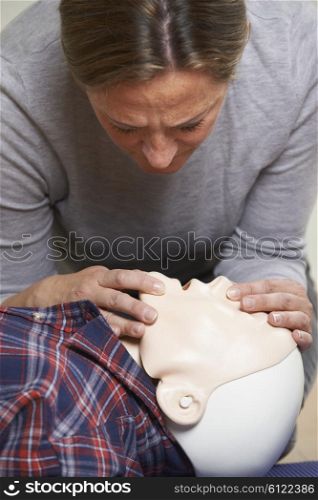 Woman In First Aid Class Performing Mouth To Mouth Resuscitation On Dummy