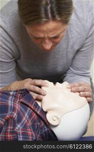 Woman In First Aid Class Performing Mouth To Mouth Resuscitation On Dummy