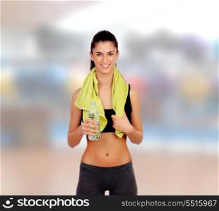 Woman in fitness with a towel drinking water isolated on a white background