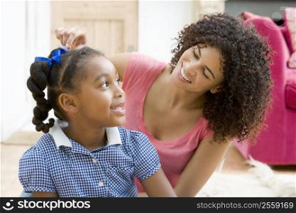Woman in front hallway fixing young girl&acute;s hair and smiling