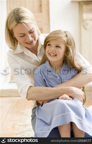 Woman in front hallway hugging young girl and smiling