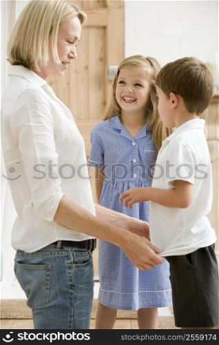 Woman in front hallway with two young children smiling
