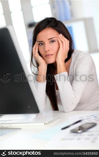 Woman in front of desktop computer having a headache