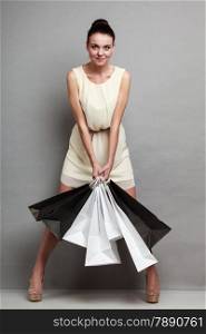 Woman in full length sale and retail concept. Girl with black and white shopping bags in hands on black and grey background in studio.