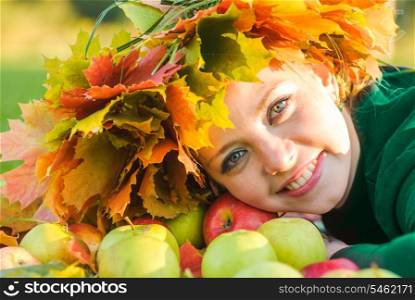 Woman in garland of maple leafs and apple crop. Autumn decorations