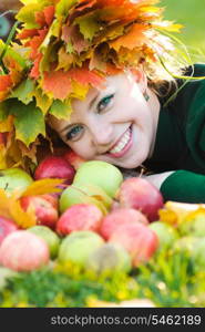 Woman in garland of maple leafs and apple crop. Autumn decorations