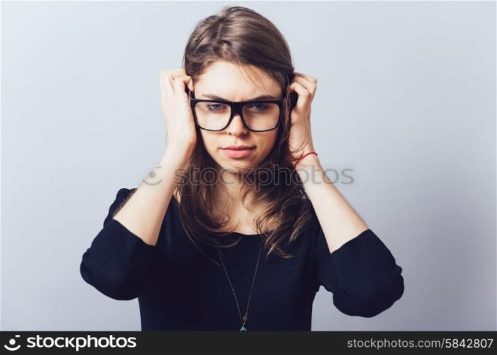 Woman in glasses, adjusts his glasses or hair on a grey background