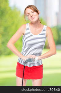 Woman in glove for game leans on golf club on a background of golf courses