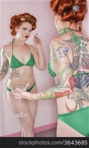 Woman in green bikini looking at herself in the mirror
