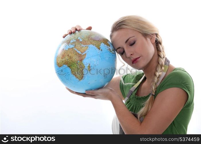 Woman in green resting her head against a large globe