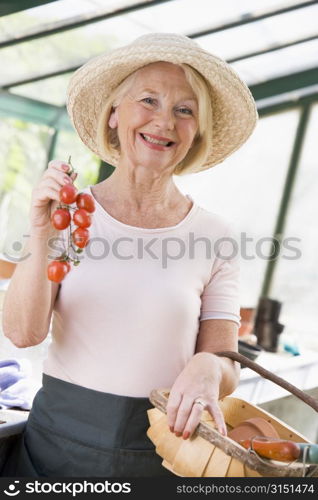 Woman in greenhouse holding cherry tomatoes smiling