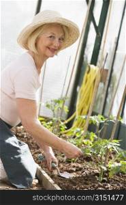 Woman in greenhouse planting seeds smiling