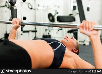 Woman in gym exercising for better fitness with a barbell