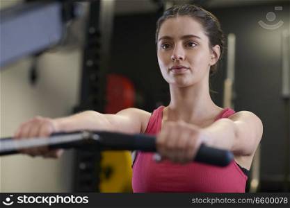 Woman In Gym Exercising On Rowing Machine