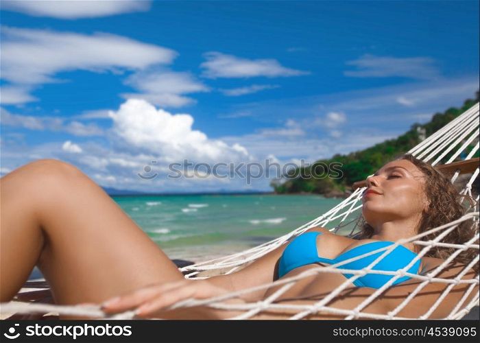 Woman in hammock on beach. Beautiful woman in bikini in hammock on sunny beach
