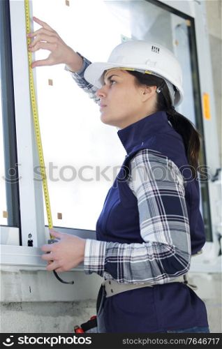 woman in hard hat measuring window
