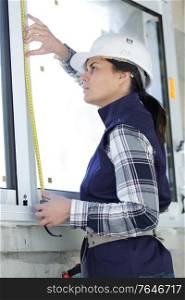 woman in hard hat measuring window