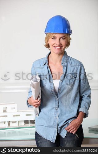 Woman in hard hat with architect&acute;s plans and model