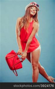 Woman in hat and red shirt with handbag sunglasses. Cute attractive young woman girl in red shirt and straw hat with handbag and sunglasses in studio on blue. Summer female fashion vogue.