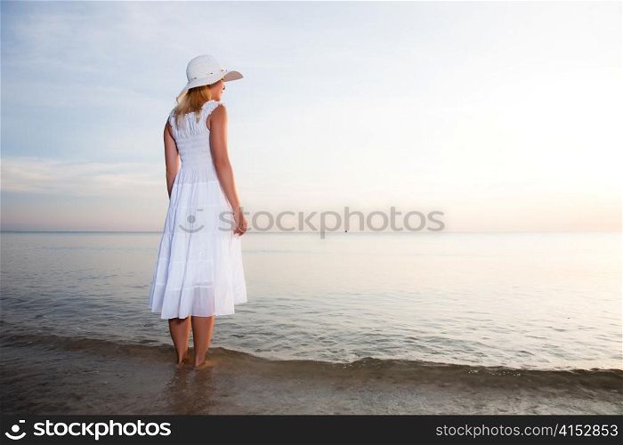 Woman in hat and white dress on the beach