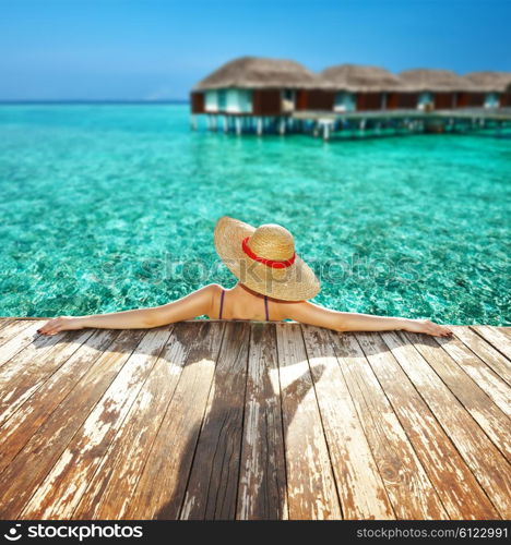 Woman in hat relaxing at beach jetty