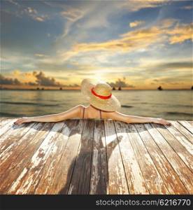 Woman in hat relaxing at beach jetty